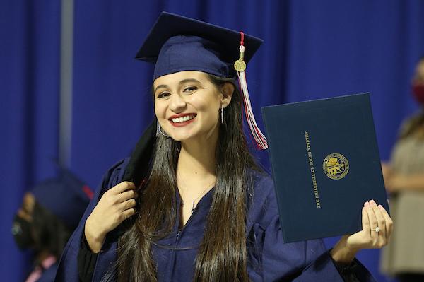 Student in cap and gown holding diploma smiling