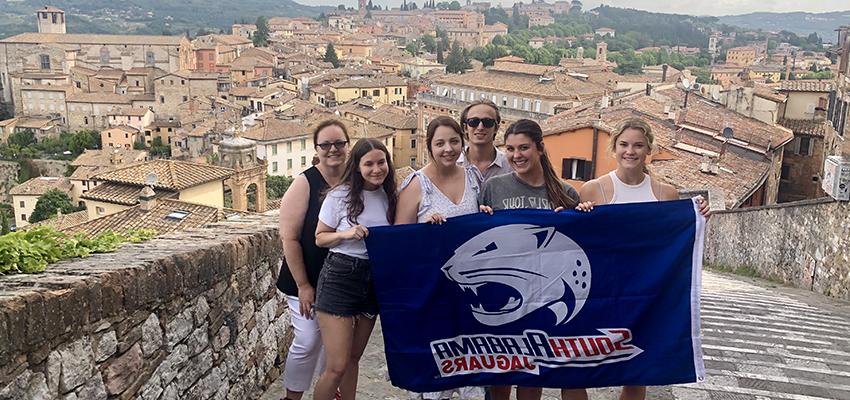 HTM Students in Italy holding Jag flag.